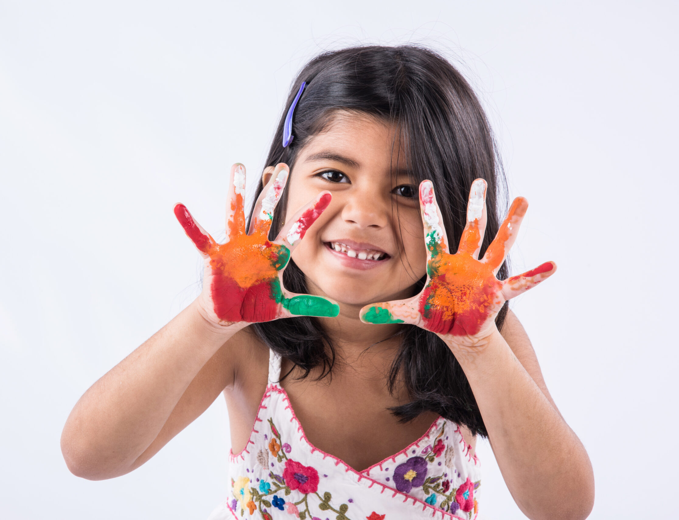 Happy Holi Greeting - Cute little Indian girl with colourful hands, isolated over white background
